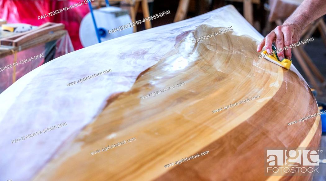 Stock Photo: 19 May 2022, Mecklenburg-Western Pomerania, Peenemünde: Time and again, Ulrich Stenberger from Raubling near Rosenheim has to wipe sanding dust off his canoe.
