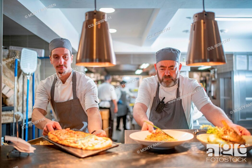 Stock Photo: Chefs presenting dishes in Italian restaurant kitchen.