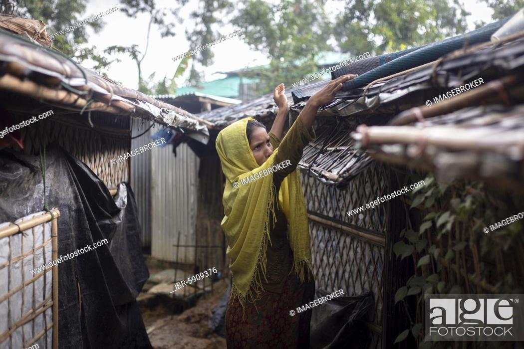 Stock Photo: Rohingya woman covers the roof of her hut with a carpet to keep the interior dry during the heavy monsoon rains, Camp Kutupalong, Cox Bazaar, Bangladesh, Asia.