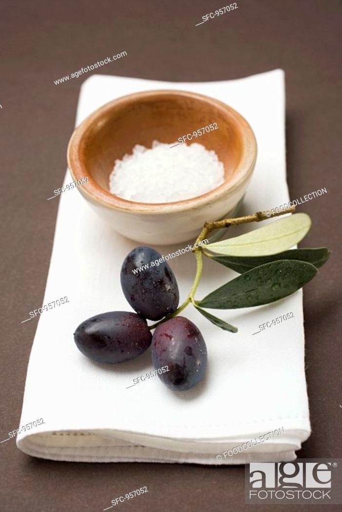 Stock Photo: Black olives on twig, sea salt in terracotta bowl.