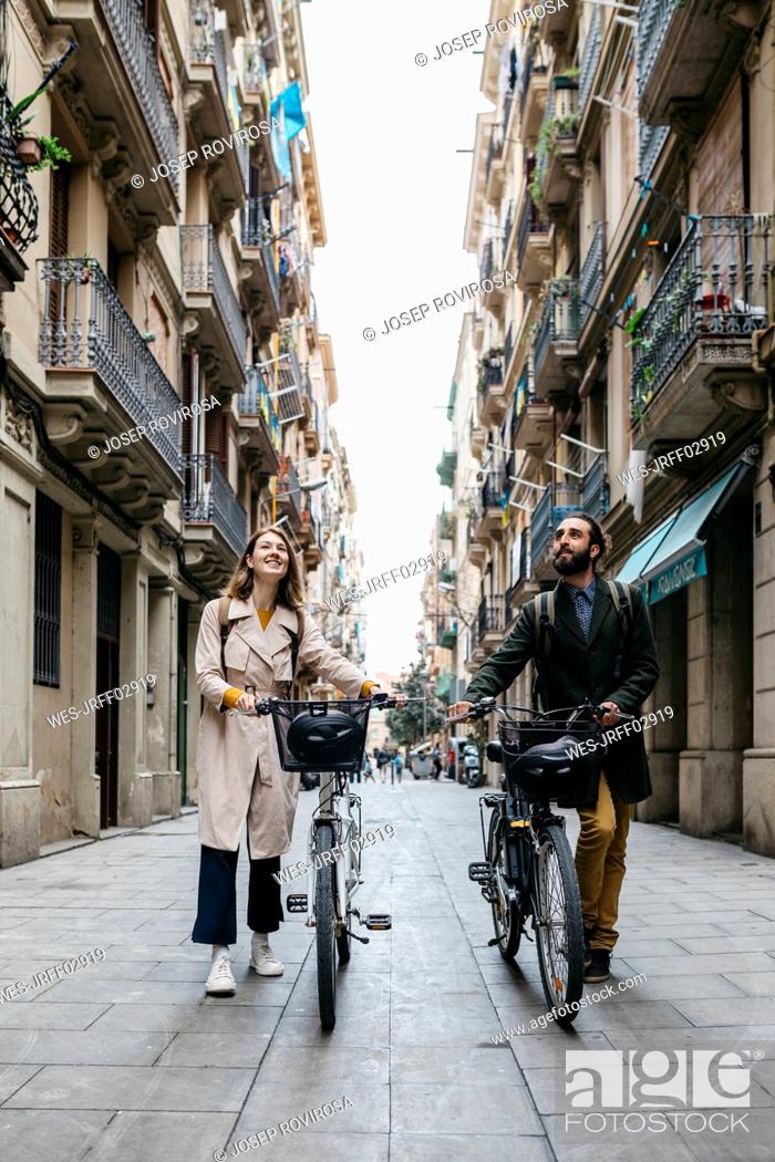 Stock Photo: Couple pushing e-bikes exploring the city.
