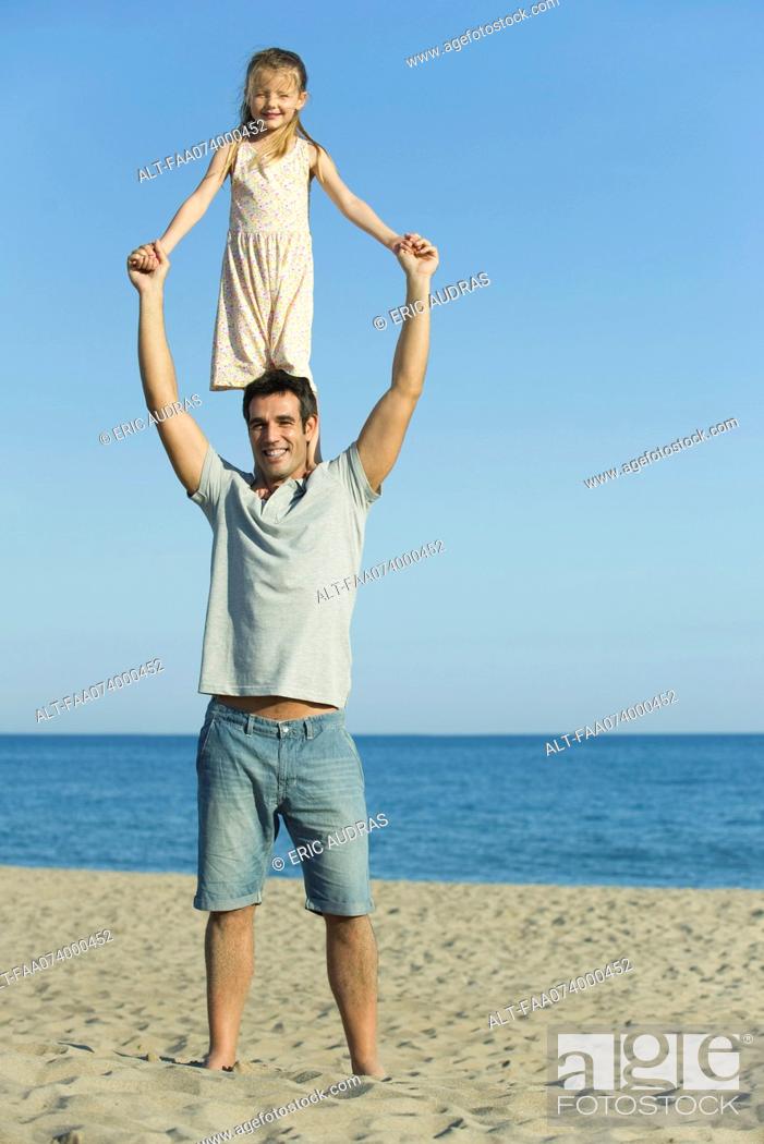 Photo de stock: Girl standing on father's shoulders at the beach.