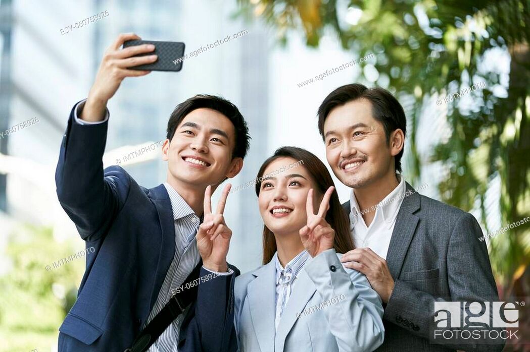 Stock Photo: team of three asian businesspeople taking a selfie in downtown financial district of modern city.