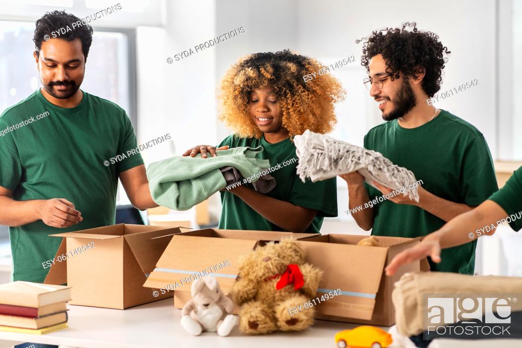 Stock Photo: happy volunteers packing stuff in donation boxes.