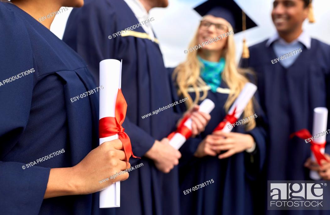 Stock Photo: graduate students in mortar boards with diplomas.
