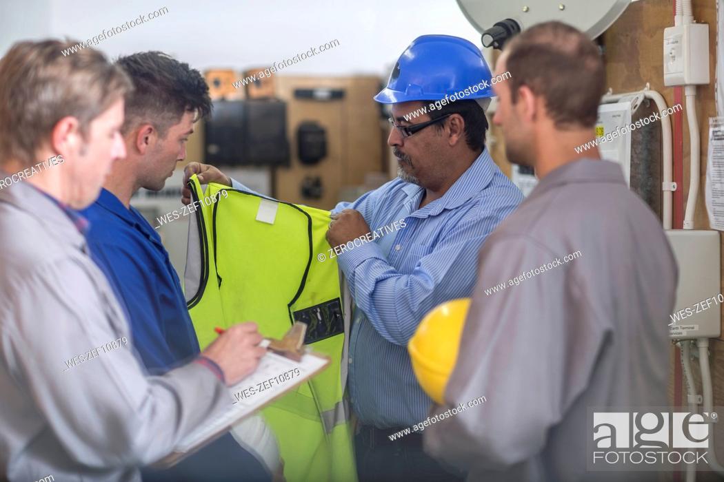 Stock Photo: Instructor in a workshop showing safety vest.