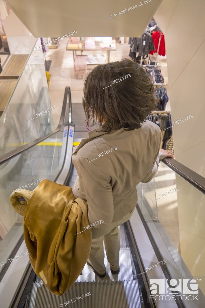 Stock Photo: Woman with her Overcoat Hanging on the Arm in a Escalator.