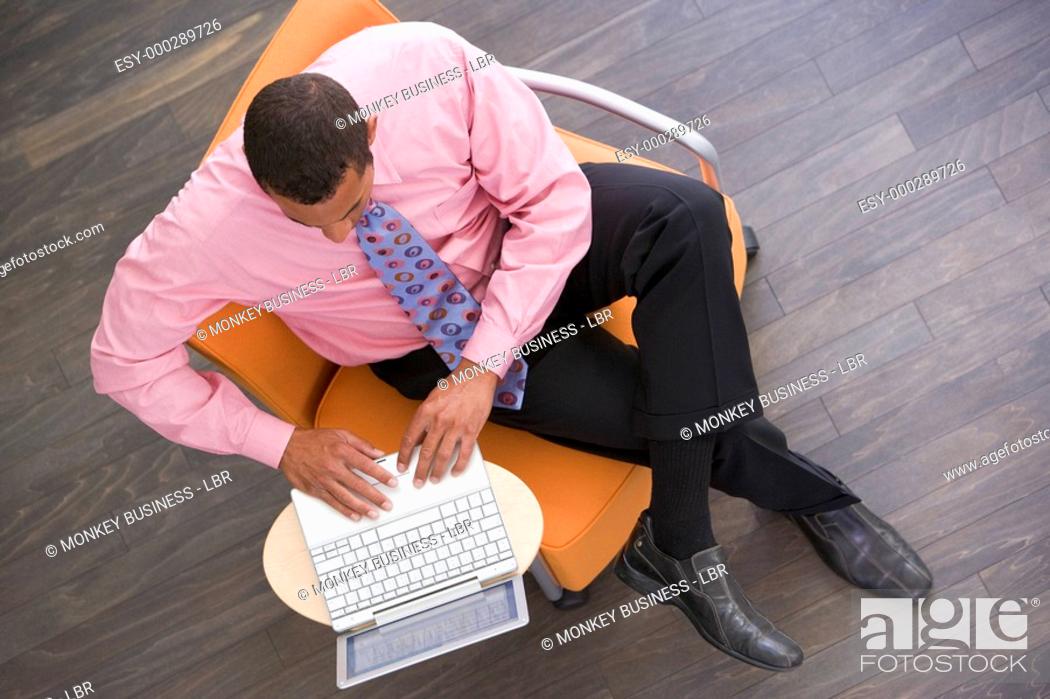 Stock Photo: Businessman sitting indoors with laptop.