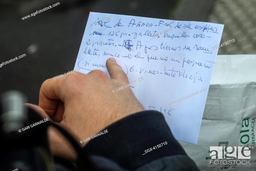 Stock Photo: Aitor, a volunteer member of the Donostia Helping Network, reads the shopping list that Rosario has made for himDonostia (Spain). April 7, 2020.