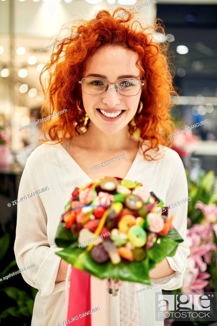 Stock Photo: Portrait of smiling woman holding candy bouquet in a shop.