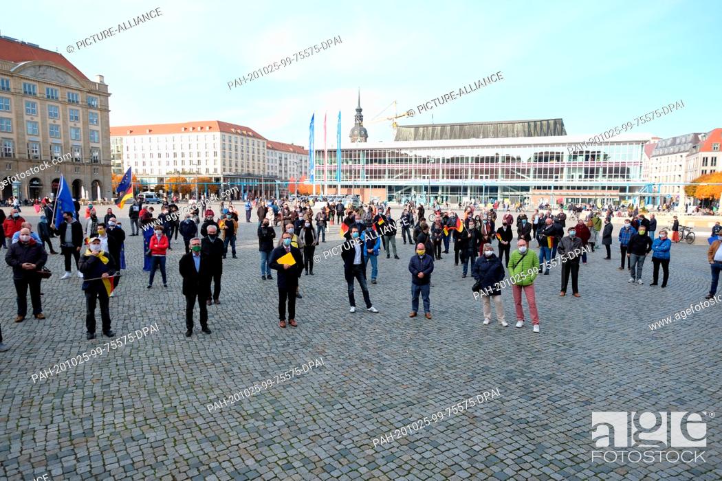 Stock Photo: 25 October 2020, Saxony, Dresden: Participants of the meeting of a civil alliance stand on the Altmarkt - all wear mouth and nose protectors and observe the.
