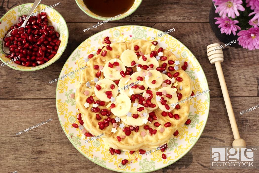 Stock Photo: Soft Belgian heart shaped waffles with banana and pomegranate, sugar decoration stars, covered with honey. Rustic wooden background, top view, close-up.