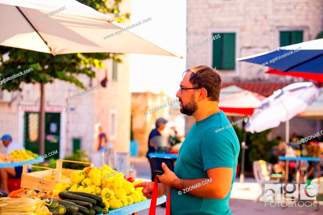 Stock Photo: Customer at a everyday morning outdoor market vegetable stand. Man is choosing fruits and vegetables, zero waste.