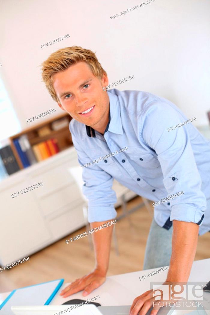 Stock Photo: Portrait of smiling attractive young man in office.