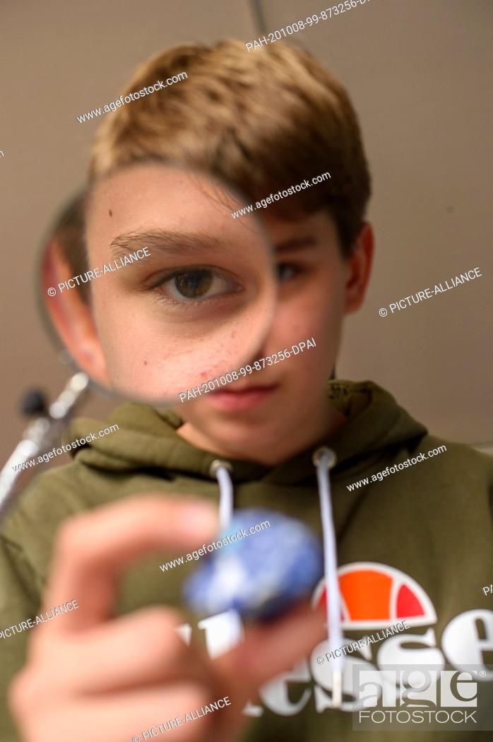 Stock Photo: 08 October 2020, Saxony-Anhalt, Magdeburg: The student Finn Koschkar examines a mineral under a magnifying glass in the geo-learning world of the New School.