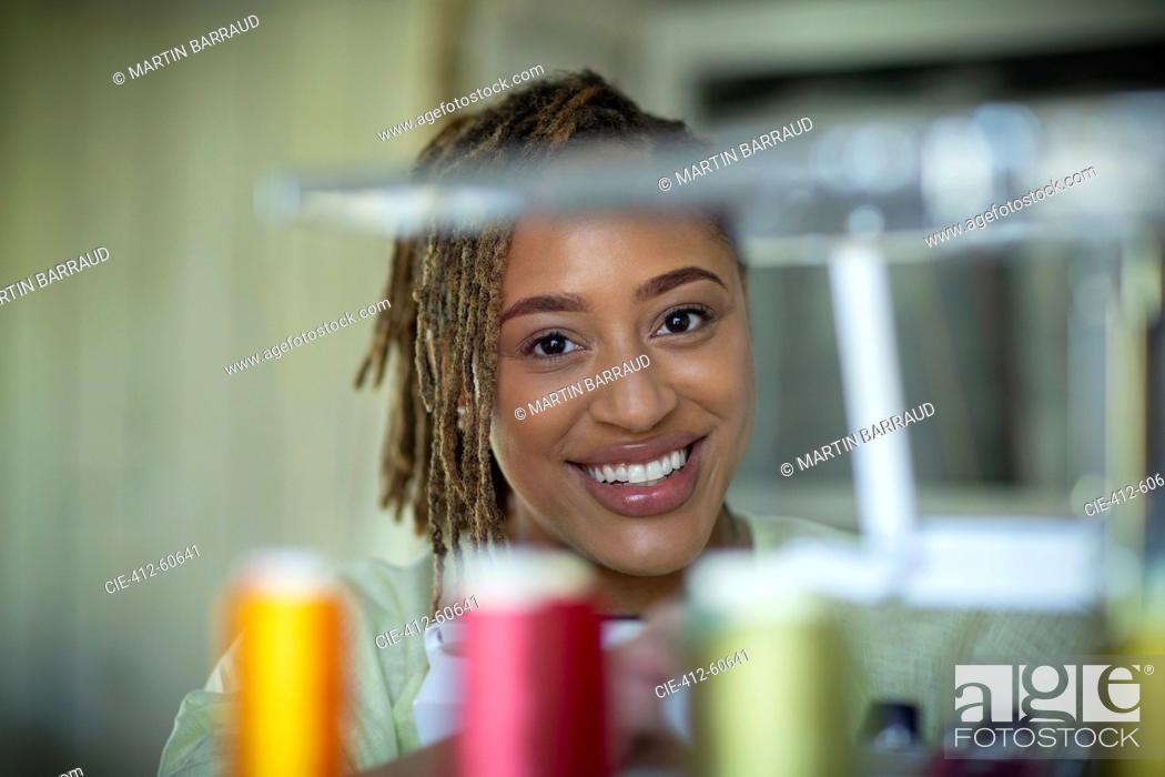 Photo de stock: Portrait happy female seamstress behind spools of thread.