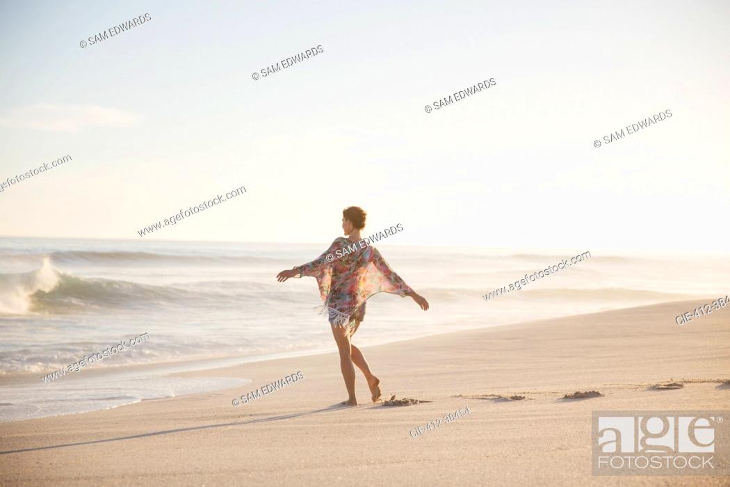 Photo de stock: Carefree woman walking with arms outstretched on sunny summer ocean beach.