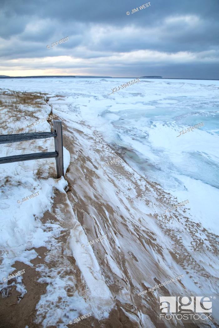 Photo de stock: Au Train, Michigan - Lake Superior in the winter. A fence guarding a walkway to the beach ends abruptly where the shoreline has been eroded.