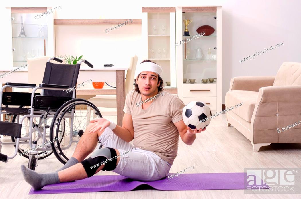 Stock Photo: Injured young man doing exercises at home.