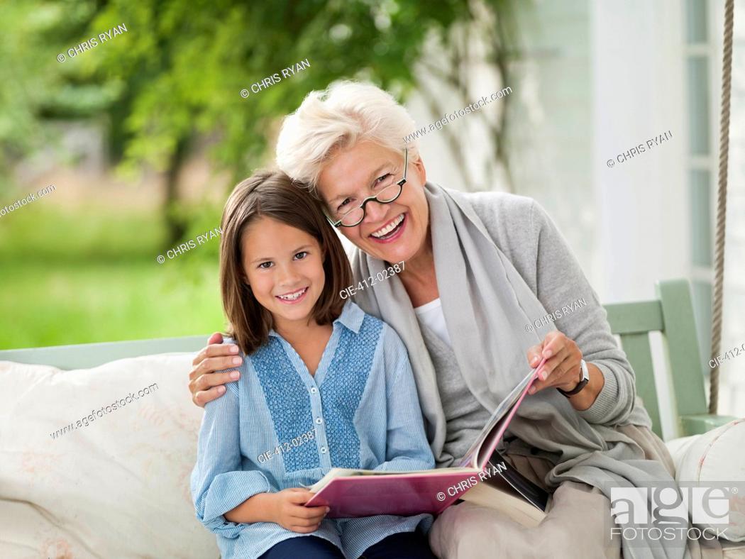 Stock Photo: Woman and granddaughter smiling in porch swing.