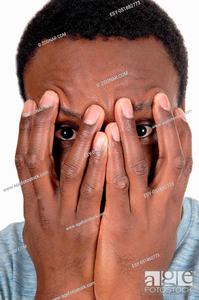 Stock Photo: A young African American man in a close up image holding his hands over his face, looking trough, isolated for white background.