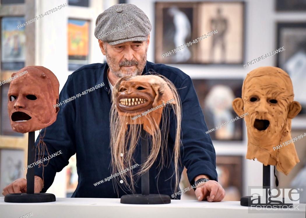 Stock Photo: FILED - 18 July 2018, Germany, Neuhardenberg: The make-up artist Wolfgang Utzt stands behind his masks in an exhibition hall of the Brandenburg Art Prize of the.