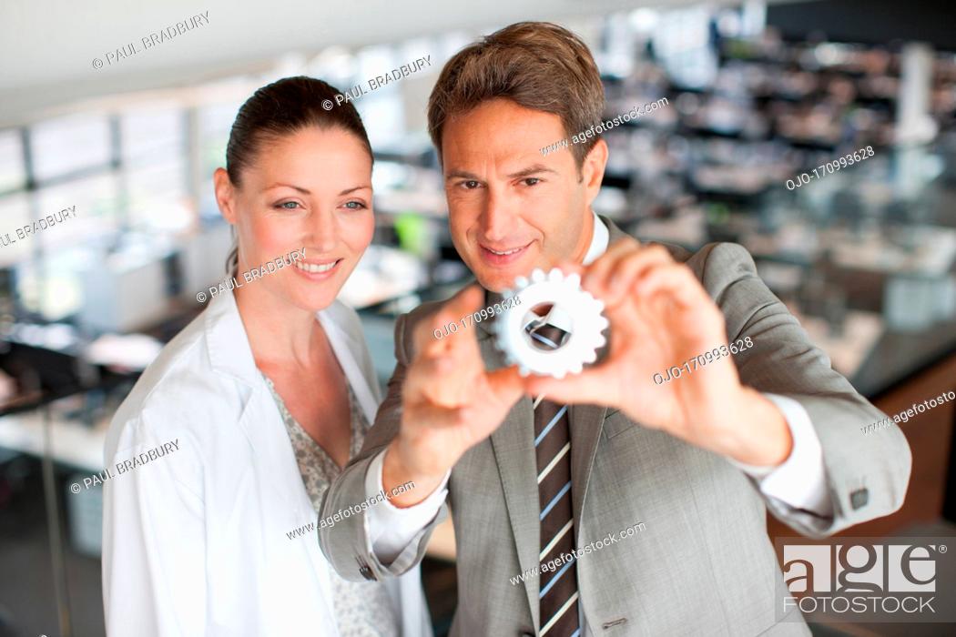 Stock Photo: Business people looking at cog.
