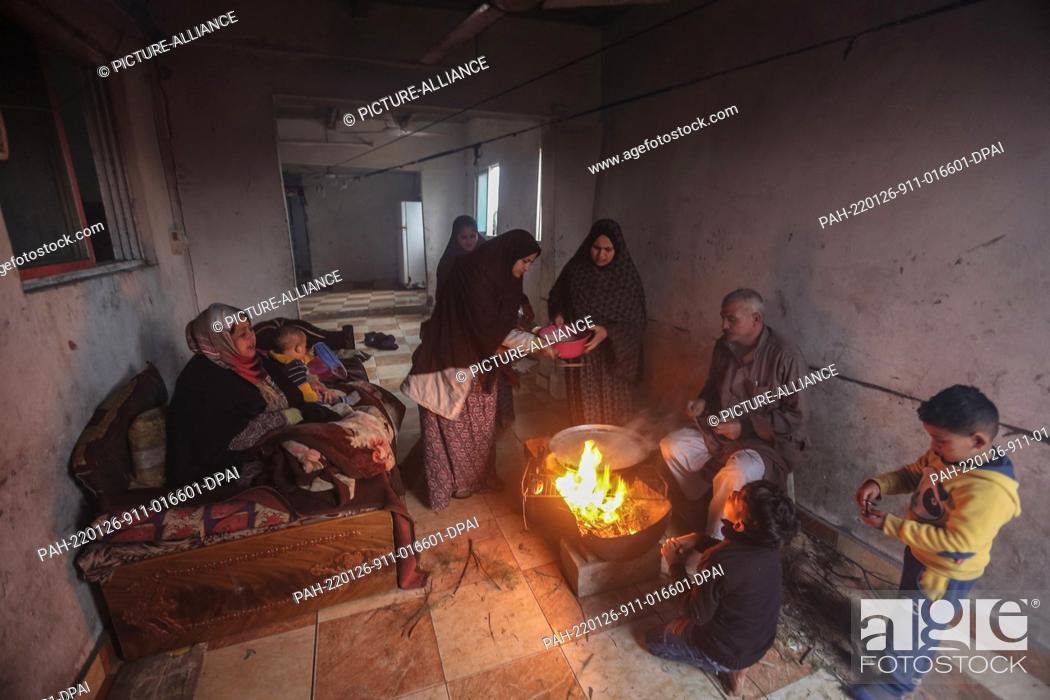 Stock Photo: 26 January 2022, Palestinian Territories, Beit Lahia: A Palestinian family burns a fire for heating and cooking indoors during the cold weather of the winter.