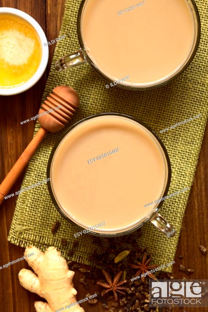 Stock Photo: Homemade Indian Masala Chai Tea made of black tea, a variety of spices and mixed with milk, honey and ingredients on the side.
