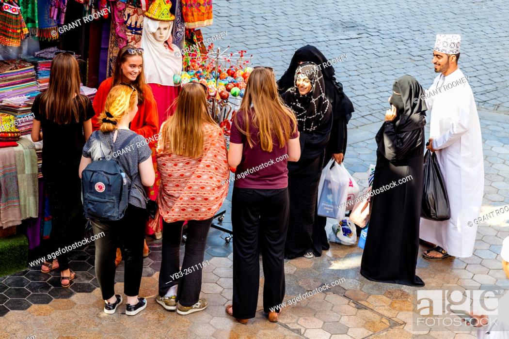 Stock Photo: Young Female Tourists Chatting With Local Omani Women, Muttrah Souk, Muscat, Sultanate Of Oman.