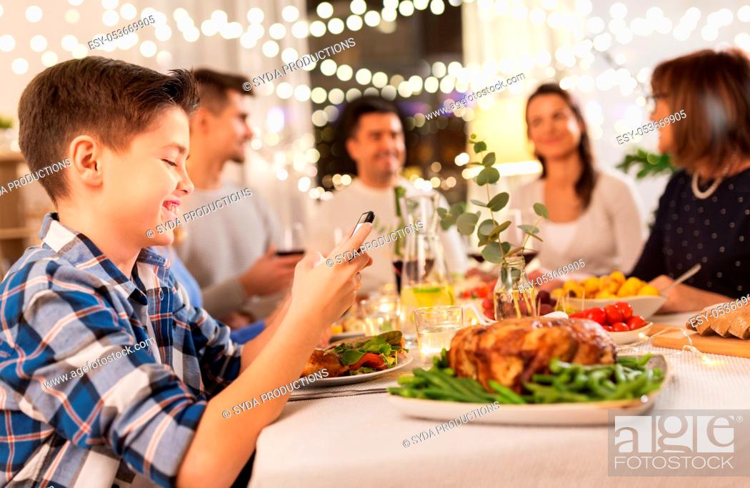 Stock Photo: boy with smartphone at family dinner party.