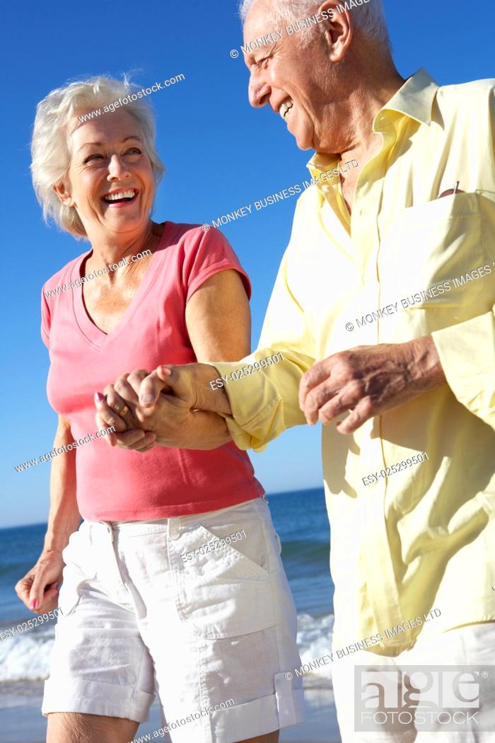 Stock Photo: Senior Couple Running Along Beach Together.