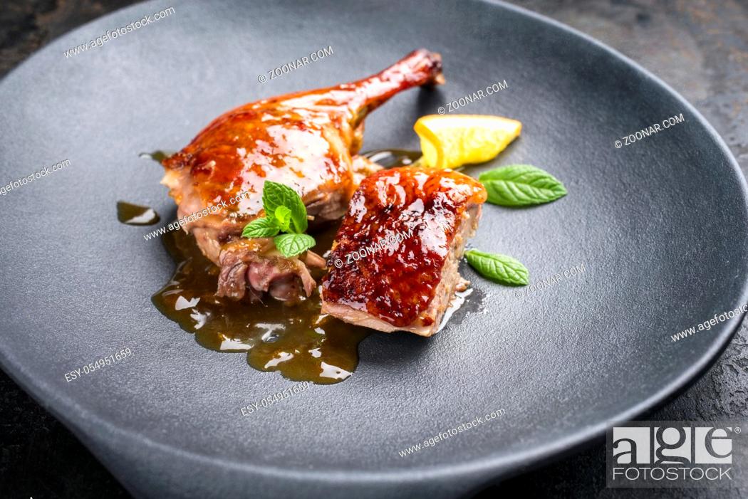 Stock Photo: Traditional roasted Christmas duck breast and leg with orange slice and herbs as closeup on a modern design plate.
