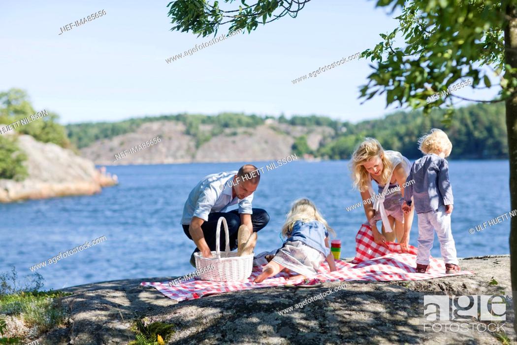 Stock Photo: Family preparing for picnic beside lake.