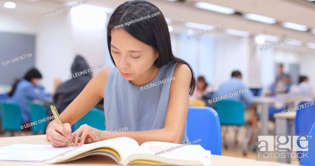 Stock Photo: Student working on her homework at library.