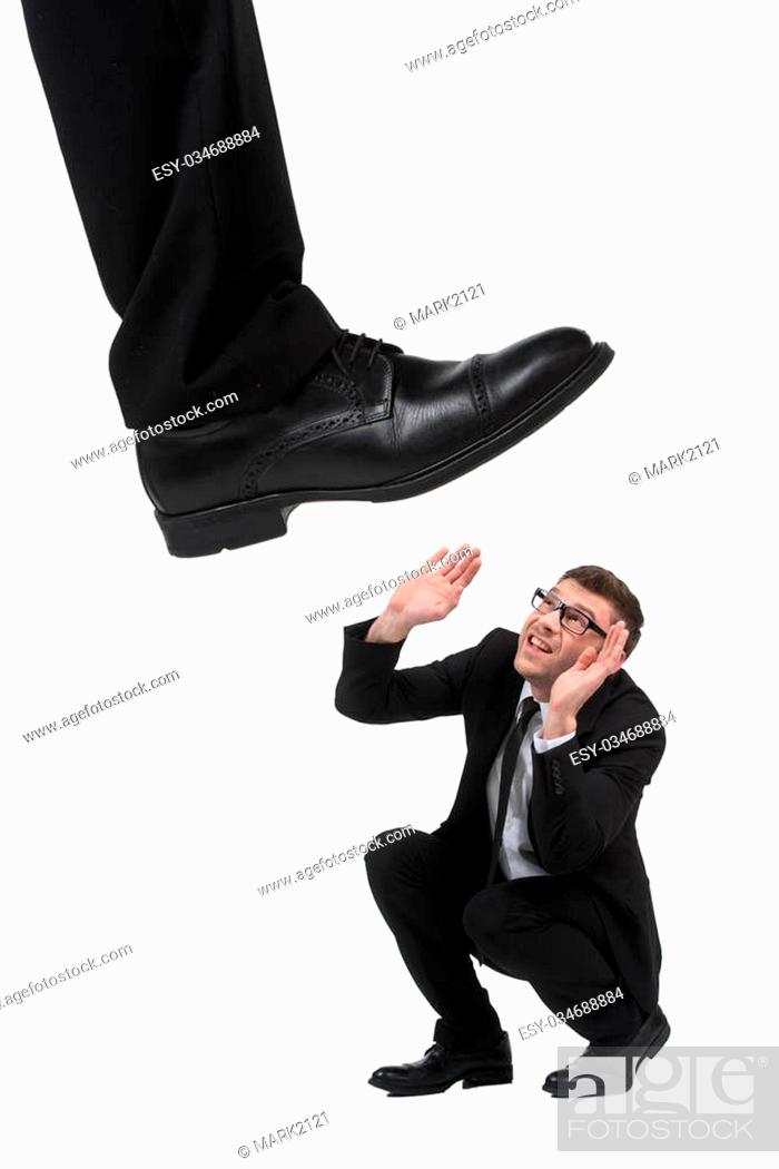 Stock Photo: Please, no! Terrified young businessmen crouching while big leg trying to step on him while isolated on white.