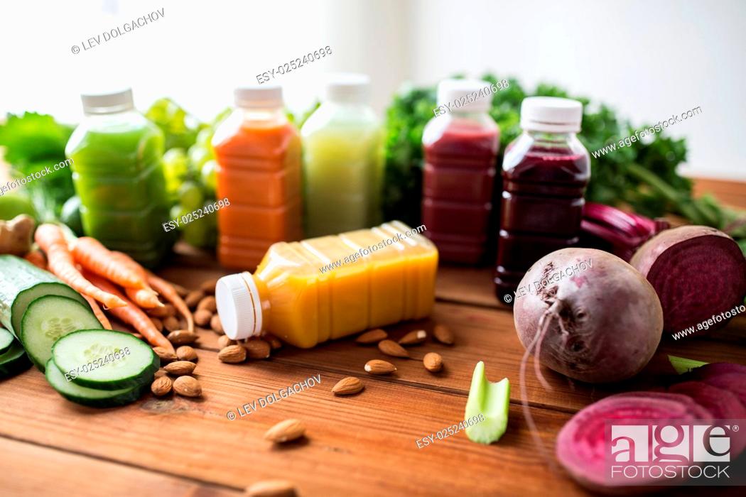 Stock Photo: healthy eating, drinks, diet and detox concept - plastic bottles with different fruit or vegetable juices and food on wooden table.