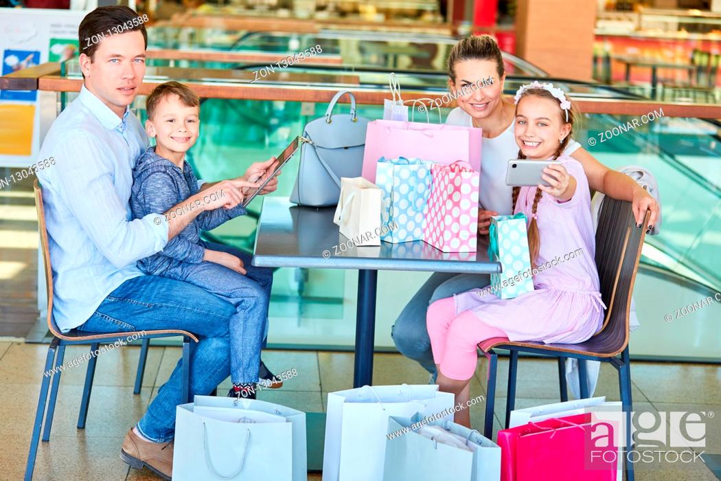 Stock Photo: Familie und Kinder mit vielen Einkaufstüten und Smartphone in Einkaufspassage.