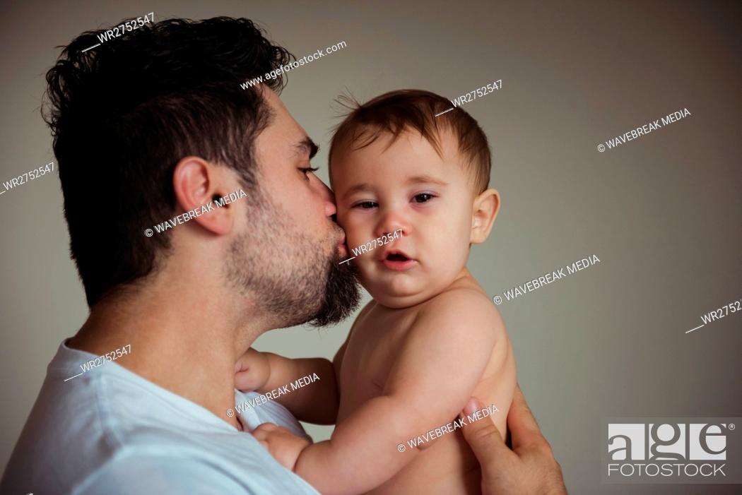 Stock Photo: Father kissing his baby on cheek.