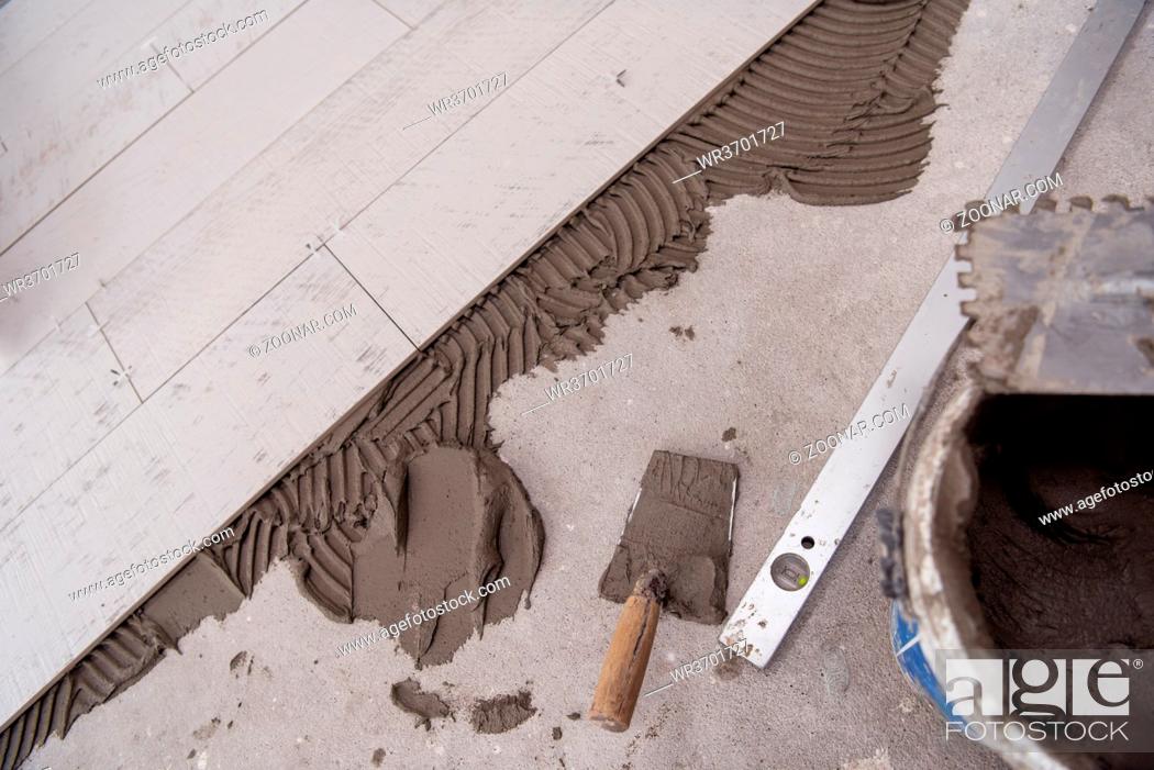 Stock Photo: Ceramic wood effect tiles and tools for tiler on the floor unfinished laying floor tiles Floor tiles installation.