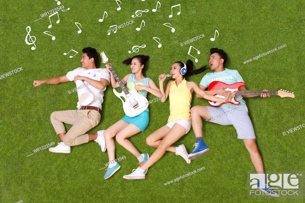 Stock Photo: Young people on grass playing musical instruments.