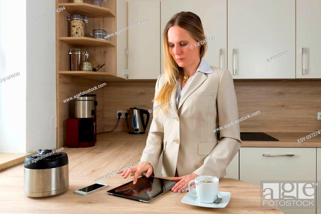 Stock Photo: Attractive, Caucasian business woman working with a tablet in the kitchen. Modern Lifestyle.