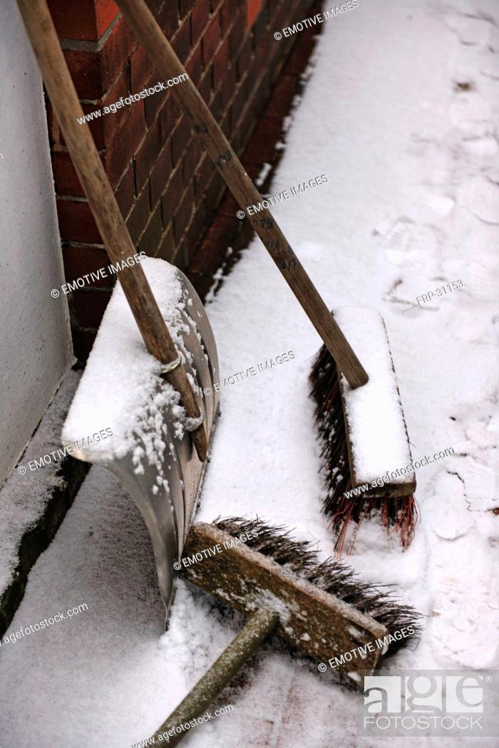 Stock Photo: Two brooms and snow shovel at house wall.