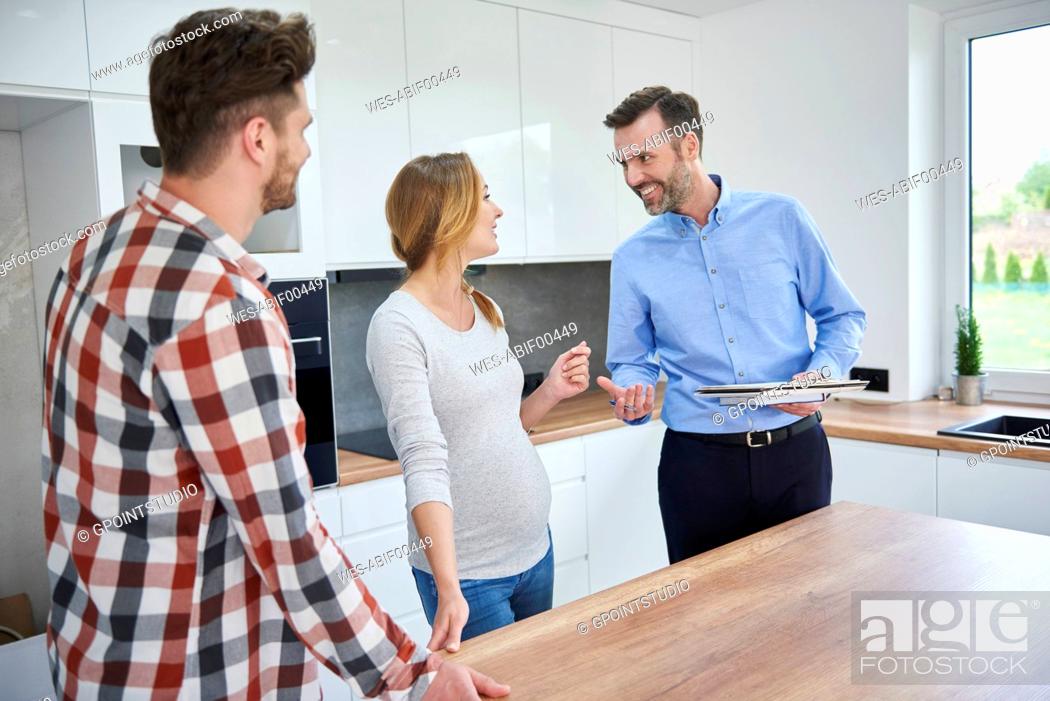 Stock Photo: Couple and real estate agent talking in kitchen of new apartment.