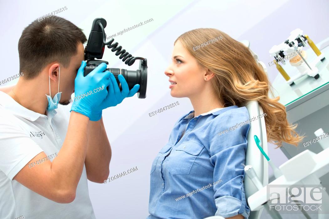 Photo de stock: Dentist with camera making shots of patients smile after treatment. Special camera with flash ring shadowless.
