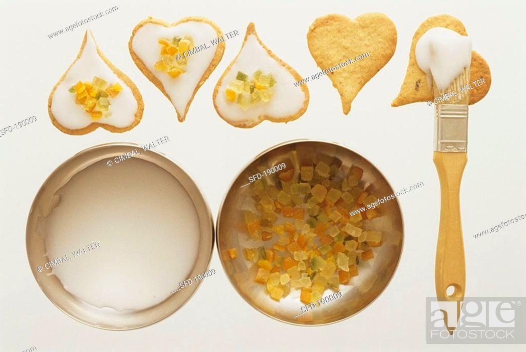 Stock Photo: Decorating heart-shaped biscuits with glace icing, candied peel.