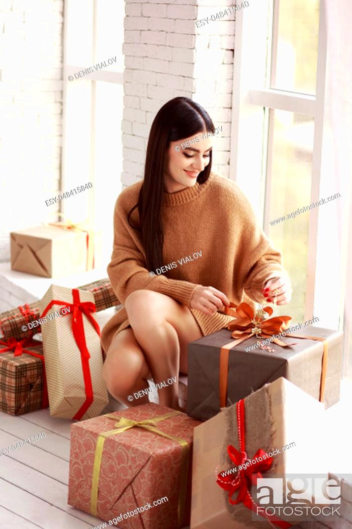 Stock Photo: Beautiful girl in sweater sitting on the window. Gifts, new year.