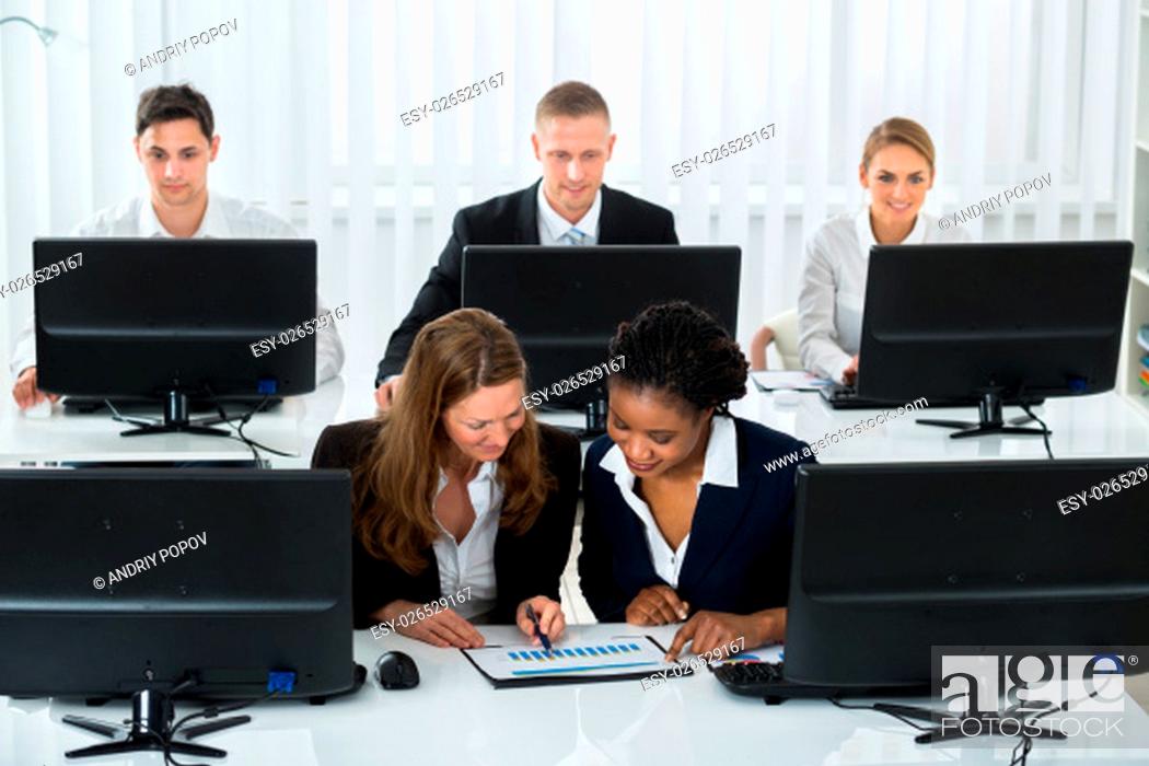 Stock Photo: Two Businesswomen Together Discussing On Graph At Workplace.