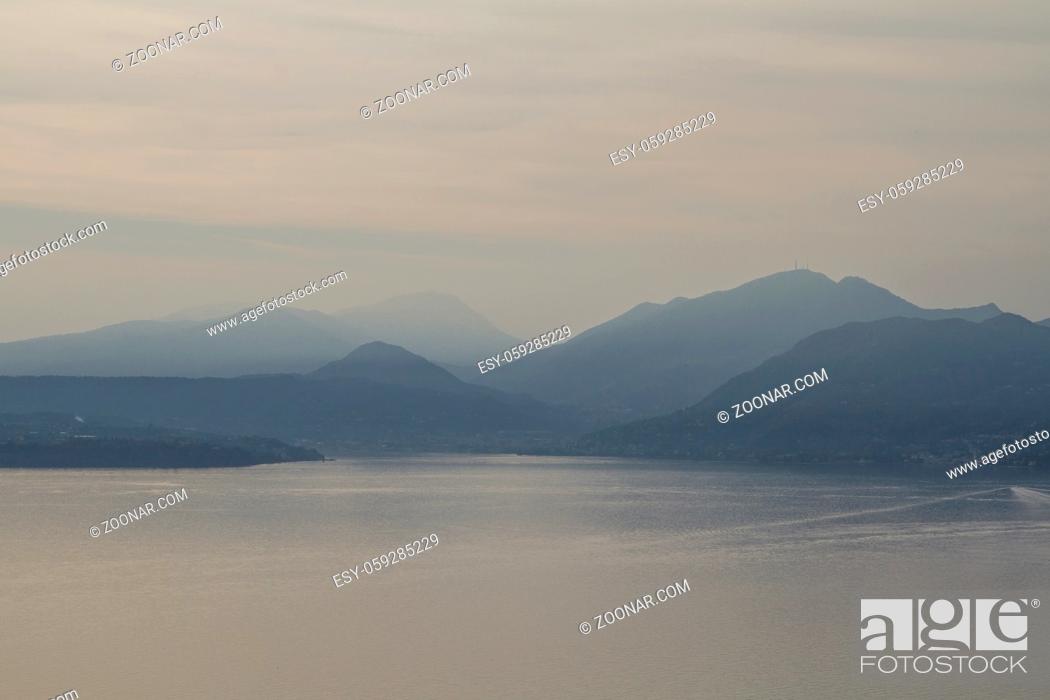 Stock Photo: Gegenlichtaufnahme des südlichen Gardasees mit den umgebenden Hügeln der Gardaseeberge.