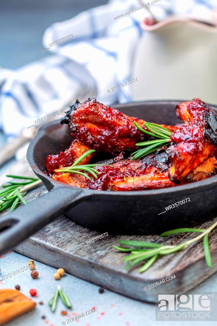 Stock Photo: Honey pork ribs with cherry sauce and rosemary in cast iron pan on grey textured background, selective focus.